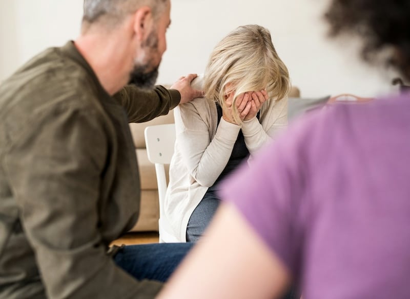 depressed woman comforted by others