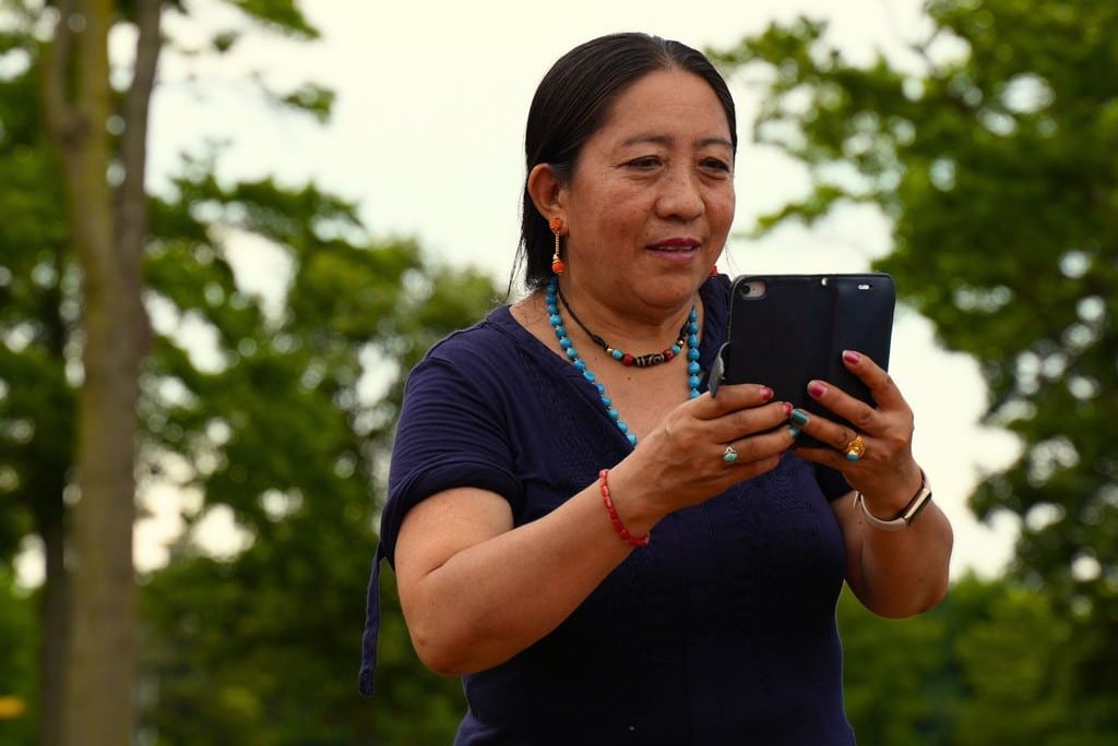 Middle-aged woman looking at a virtual meeting on a smartphone.